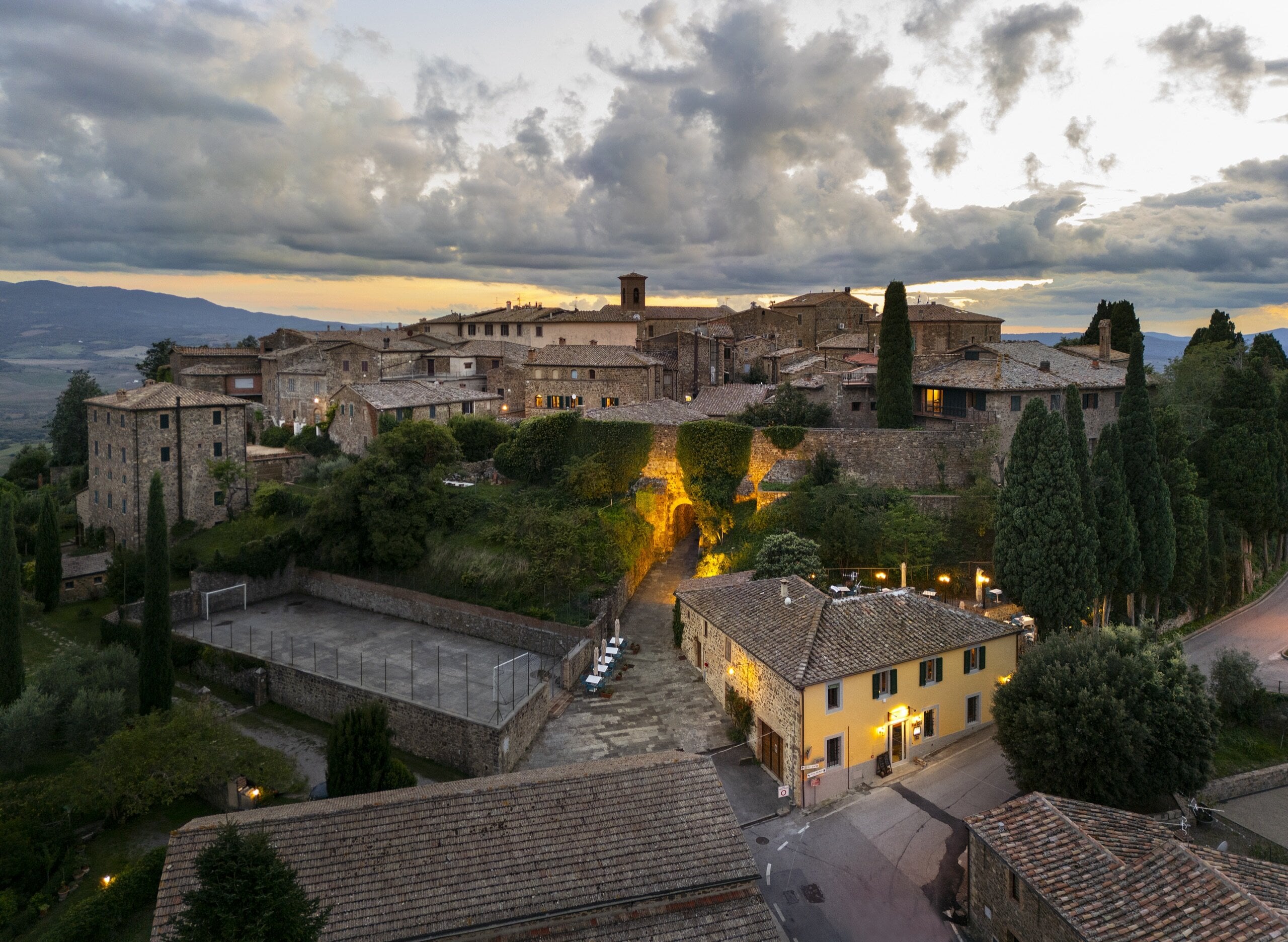 Sant'Angelo in Colle dall'esterno delle mura, al tramonto, con il Monte Amiata all'orizzonte